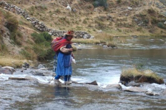 Local woman crossing river in Huaraz